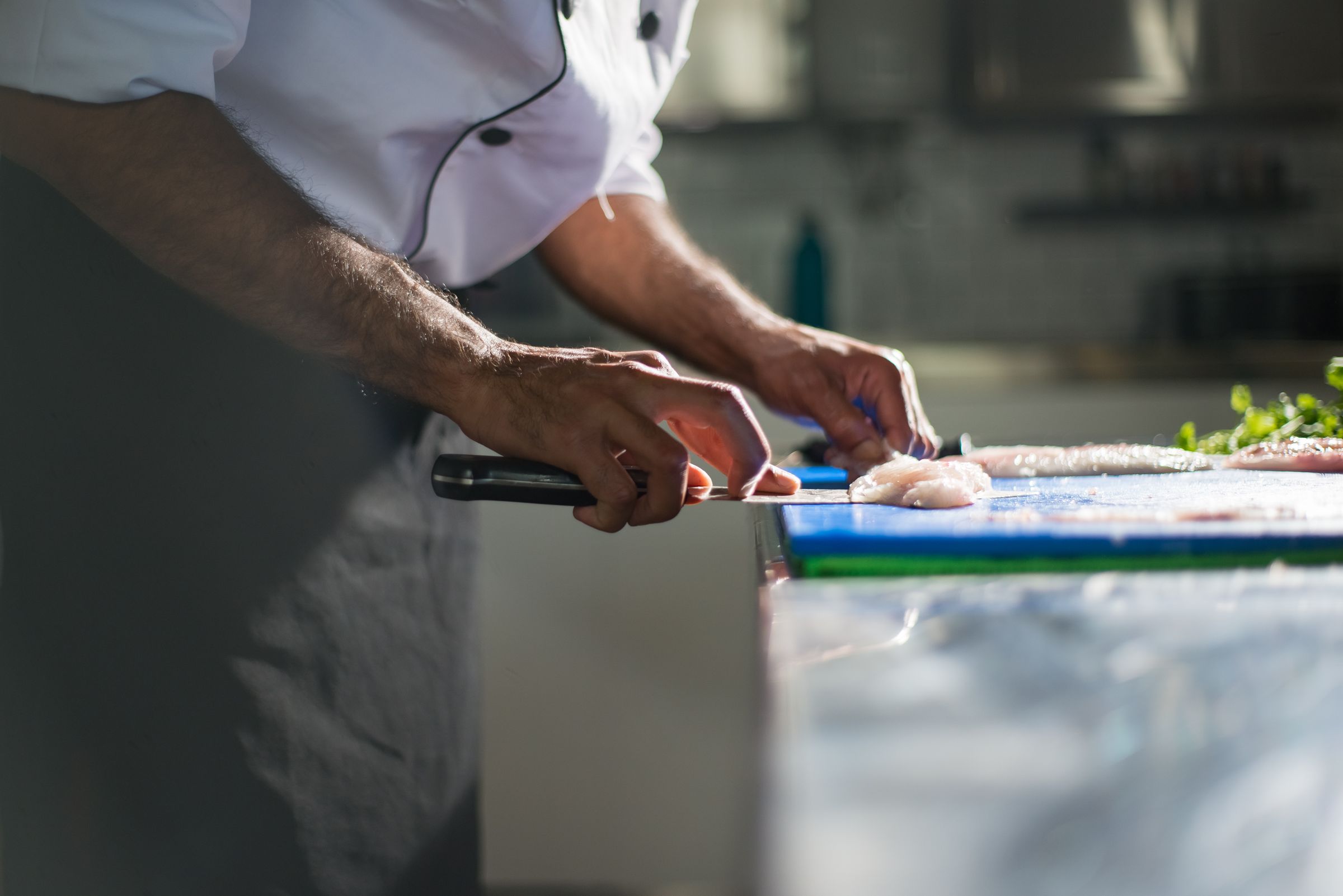 Executive chef filleting fish during pre-opening kitchen prep