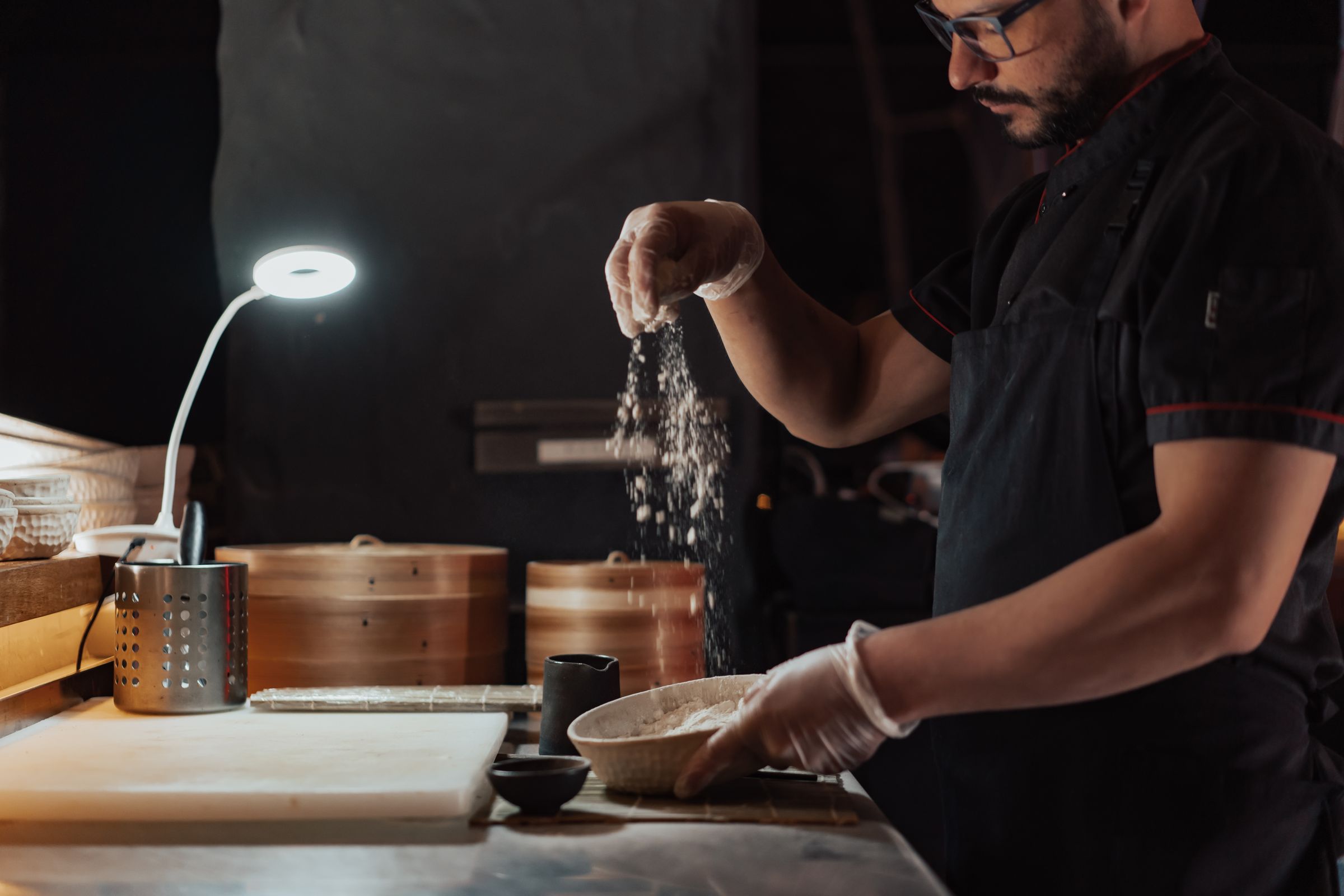 Head chef sifting flour beside bamboo steamers in the Camberwell kitchen